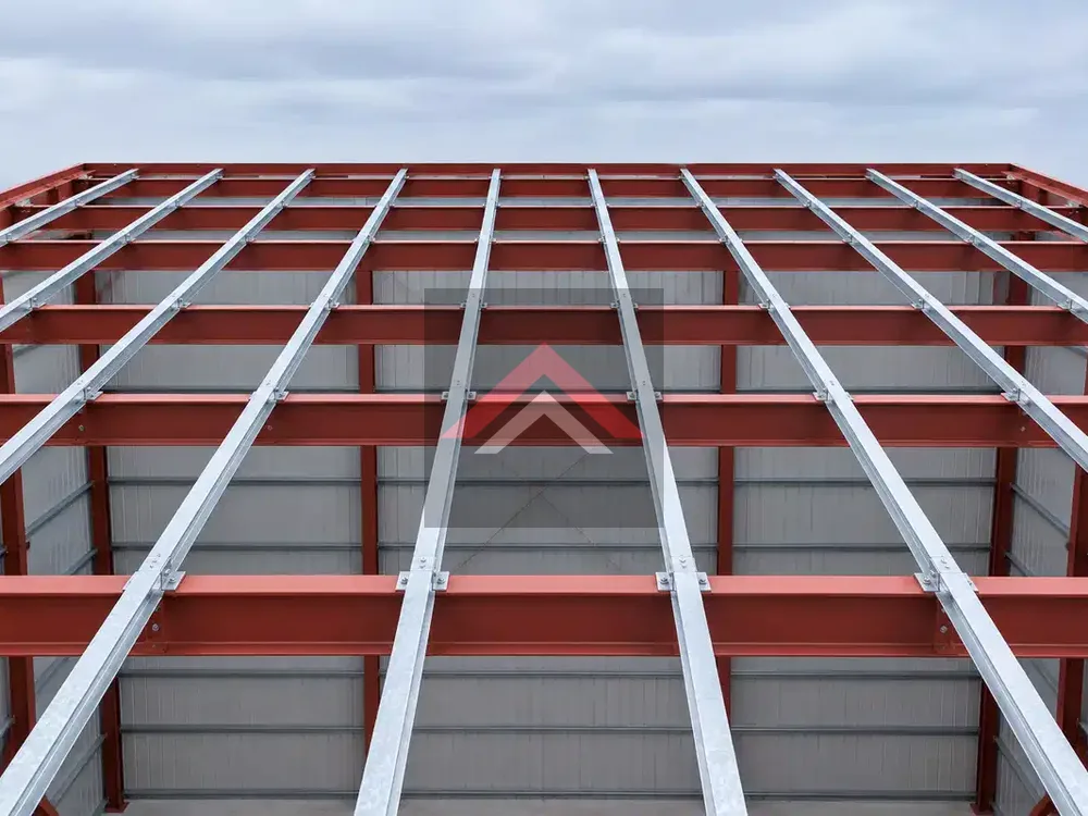 Exposed red steel beams and galvanized metal purlins on a commercial building roof before metal roofing panels are installed in Beaumont, TX.